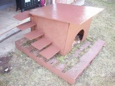 a cat house built into the side of a wooden fence with steps leading up to it