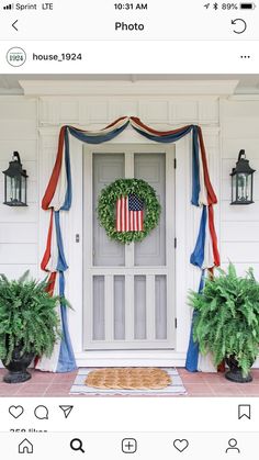 an american flag wreath on the front door of a white house with potted plants