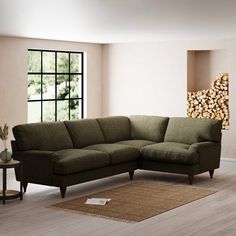 a living room with a large sectional couch and wooden floors in front of a window