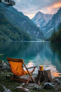 an orange chair sitting on top of a grass covered field next to a lake