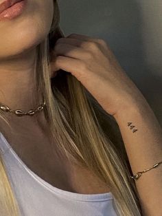 a woman with long blonde hair wearing a white tank top and gold chain choker