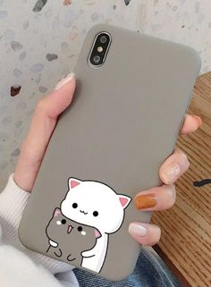 a woman holding up a phone case with a cat on it