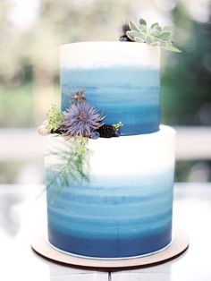 two tiered blue and white cake with flowers on top