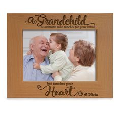 a wooden frame with an image of a man holding a baby and the words, grandchild is someone who reaches for your hand but touches your heart