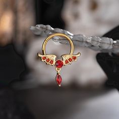 This wings shape red gems dangle septum ring design is so dainty. The three different choices bring out distinctive sensations due to the change of color and gem combinations.The gold one exudes royal elegance. The black one with red CZ gems encapsulates an air of mystery and intrigue. The steel one offers a sense of purity and divine spirit. You can easily pick which one suits you the best, or take them all for a change of looks and moods. Dainty Septum Ring, Dainty Septum, Titanium Belly Button Rings, Divine Spirit, Red Gems, Conch Hoop, Dangle Belly Rings, Dragon Claw, Skull Hand