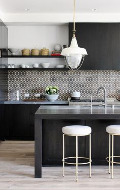 a kitchen with black cabinets and white stools