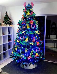 a brightly lit christmas tree in the corner of a room with bookshelves and shelves