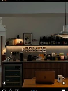 an open laptop computer sitting on top of a wooden table next to a wine rack