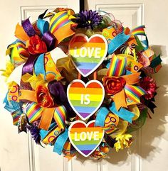 a colorful wreath with two hearts and the words love is love painted on it in rainbow colors