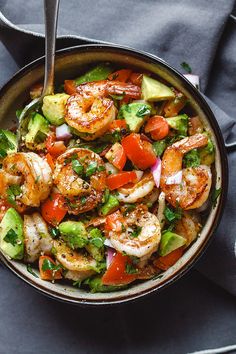 a bowl filled with shrimp, avocado and tomatoes