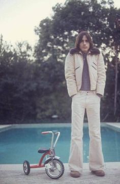 a man standing in front of a pool next to a tricycle