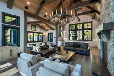 a living room filled with lots of furniture and a chandelier hanging from the ceiling