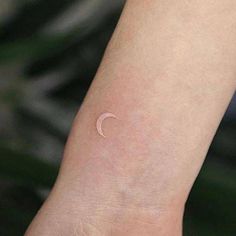 a small white crescent tattoo on the wrist