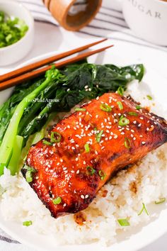 a plate with rice, broccoli and salmon on it next to chopsticks