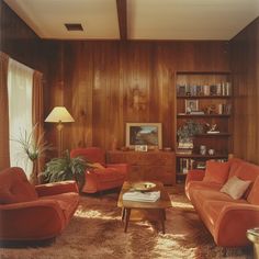 a living room with wood paneling and orange furniture