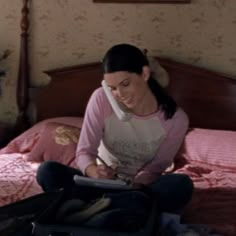 a woman sitting on top of a bed next to a suitcase with a pen in it