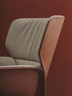 an upholstered chair in front of a red wall with the seat folded back