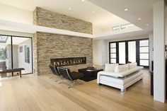 a living room with white furniture and a stone fire place in the middle of it