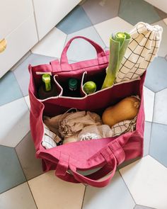 a pink bag filled with groceries sitting on top of a tiled floor