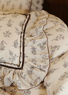 an unmade bed with white and blue floral bedspread on top of it