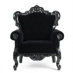 a black chair with ornate carvings on the armrests and foot rests against a white background