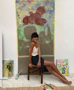 a woman sitting on a chair in front of a painting