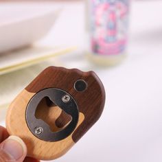 a person holding a wooden bottle opener in their hand