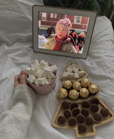 a person holding a bowl of chocolates next to a table full of cupcakes