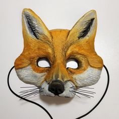 a fox mask is shown on a white surface with black wires in front of it