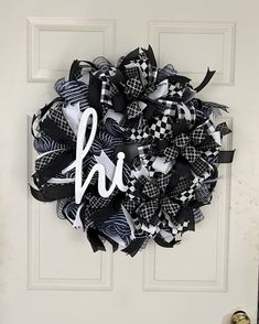 a black and white wreath with the letter h on it is hanging on a door