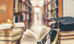 an open book with a graduation cap on top of it next to stacks of books