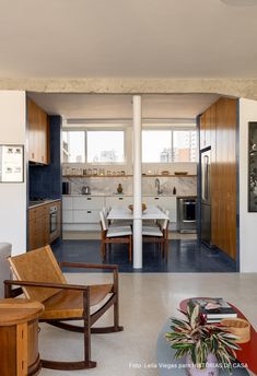 an open kitchen and living room area in a modern home with white walls, blue flooring and wooden furniture