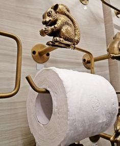 there is a gold squirrel on top of a toilet roll holder and it's attached to the wall