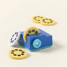 a toy camera with two yellow and blue buttons on the side, sitting next to each other