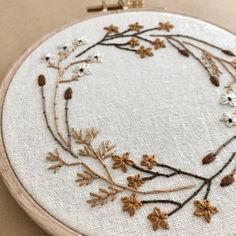 a close up of a embroidery on a wooden hoop with flowers and leaves in it