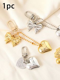 four different types of bell charms on a white sheet with gold chains and silver bells