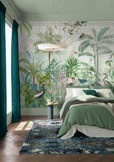 a bedroom decorated in green and white with tropical plants on the wall behind the bed