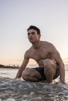 a shirtless man kneeling in the water