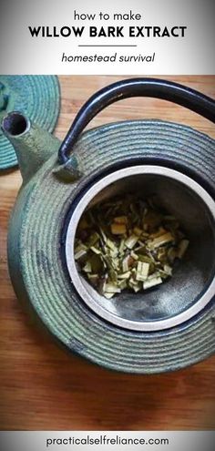 a teapot filled with green leaves on top of a wooden table