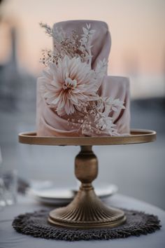 a three tiered cake with flowers on it sitting on top of a gold plate