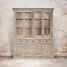 an old wooden china cabinet with glass doors on the top and bottom, in front of a stucco wall