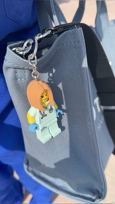 a lego minifigure keychain is attached to a purse with a lego figure on it