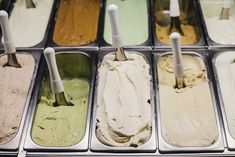 an assortment of ice creams in trays with spoons