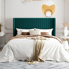 a bedroom with a green velvet headboard and white bedding, gold accents on the wall