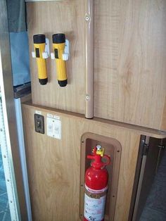 two fire extinguishers are attached to the side of a wooden cabinet