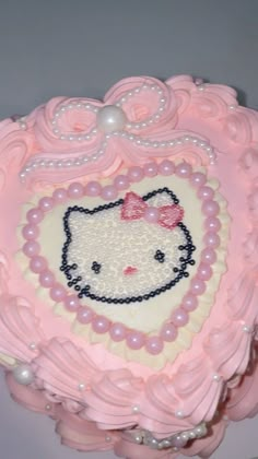 a hello kitty cake with pearls and bows on it's head is decorated in pink icing