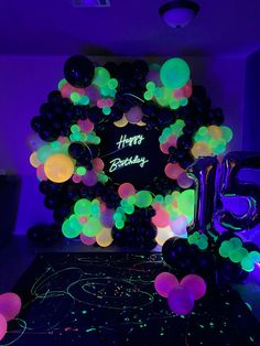 a birthday party with balloons and neon lights on the wall, including a large balloon arch