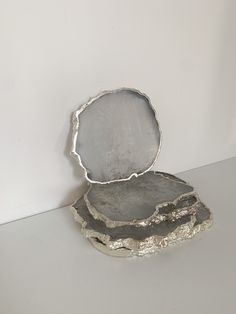 a piece of metal sitting on top of a white table next to a wall with a mirror in it