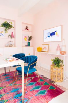 a living room with pink walls and colorful rugs on the floor next to a white table