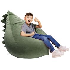 a young boy sitting on a dinosaur shaped bean bag chair giving the thumbs up sign